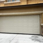 Closed beige garage door on a modern house with stone accents and the street number 10172 visible.